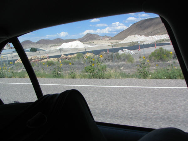 a mound of white dirt beside an industrial plant out in the middle of nowhere.