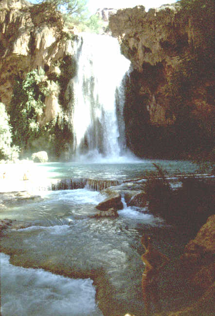 A young woman in a white bakini gazes at the falls.