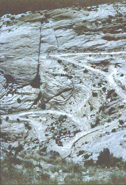 A shere rock wall is criss-crossed with a steep trial.